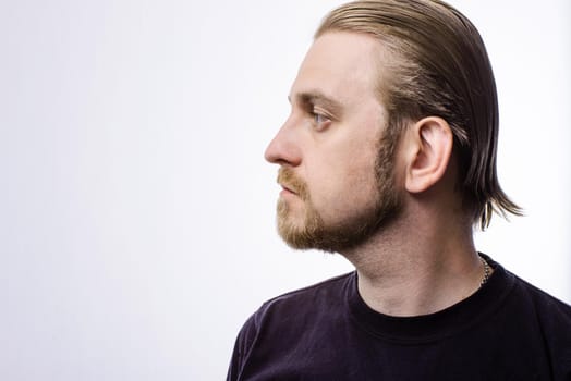 Portrait of an attractive blond hipster beard in profile on a gray background