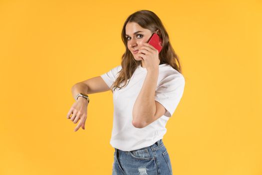 Tula, Russia - September 23,2020: Beautiful young woman with new model iphone and apple watch talking on smartphone.