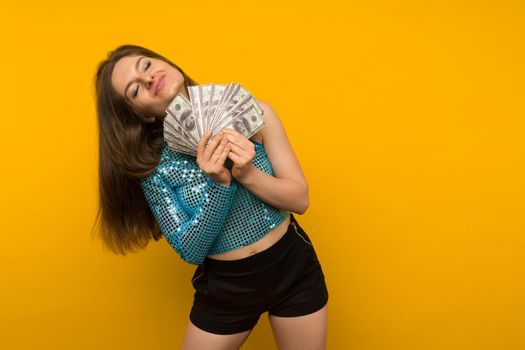 Joyful girl won the lottery and holds a fan of US dollars in her hands on a yellow background - image