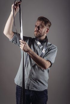 trendy man looks at the quality of the captured film on gray background.