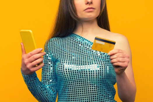 Lady buying online with a credit card and smart phone on yellow background - image