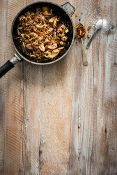 fried meat in pan on wooden table with text space