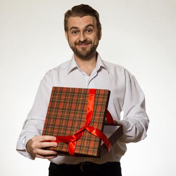 Handsome man in white shirt holding open gift box tied with a red ribbon