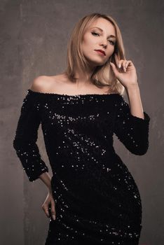 Portrait of beautiful young blonde girl in black dress. Fashion photo