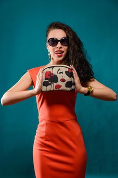 Beautiful girl with a sunglasses and clutch bag in her hands.