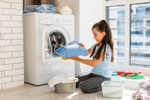 Happy little girl doing laundry in home interior