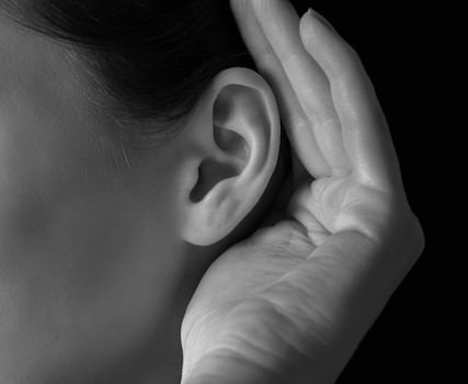 Unrecognizable woman holds her hand near ear and listens, close-up