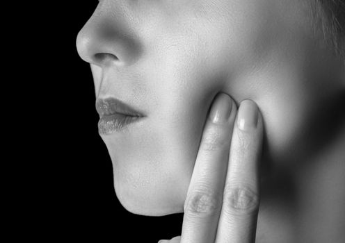 Woman is touching her cheek, toothache, monochrome image