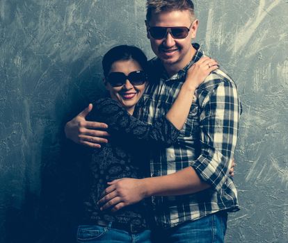 smiling couple with sunglasses on grey background
