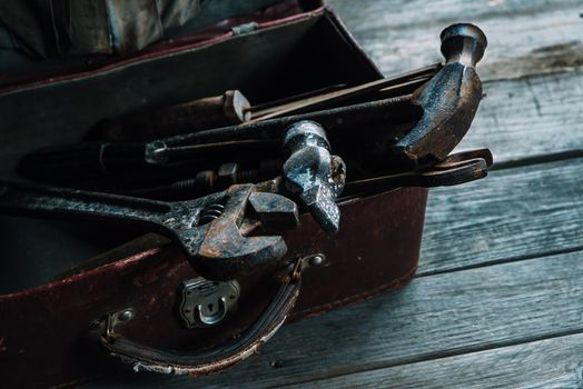 Set of old working tools in the suitcase on wooden background