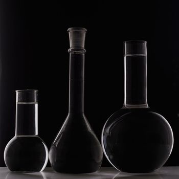 Laboratory equipment, three glass flask on black background.