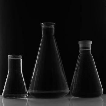 Laboratory equipment, three glass flask on black background.