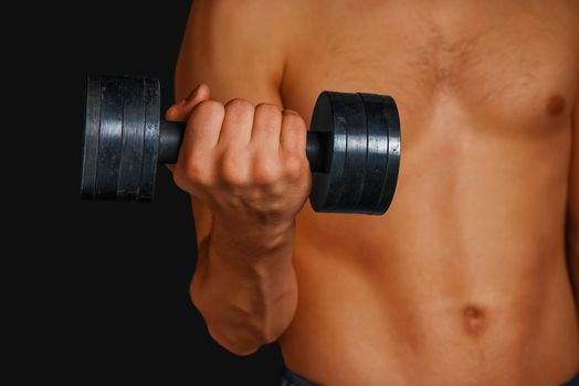 Muscular shirtless man is lifting dumbbell, face is not visible