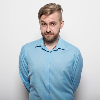 Hipster man in blue long-sleeved shirt, studio shot.