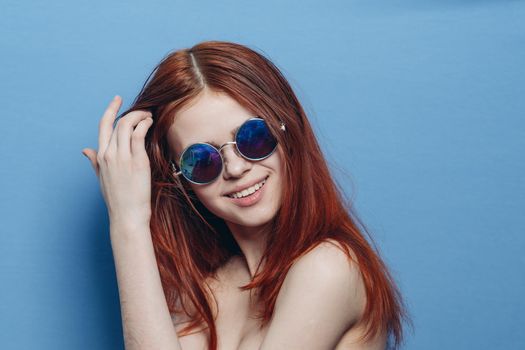 perky red-haired woman in blue glasses bare shoulders posing. High quality photo