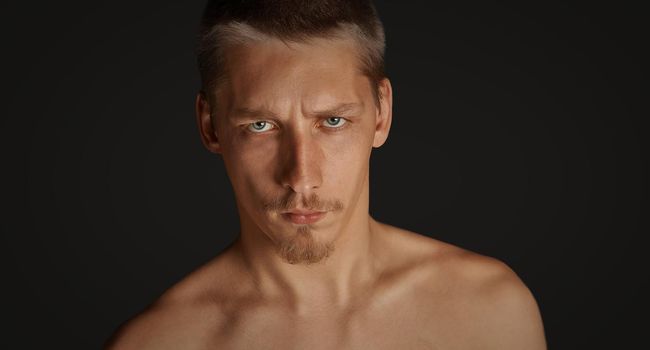 Portrait of young serious man on black background
