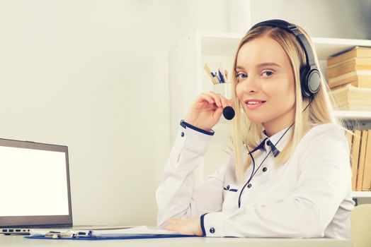 Portrait of happy smiling female customer support phone operator at workplace. - Image toned