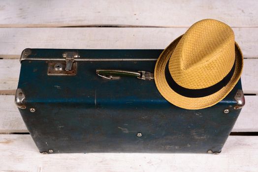 Old vintage, retro suitcase and a straw hat on a white wooden floor. Travel concept