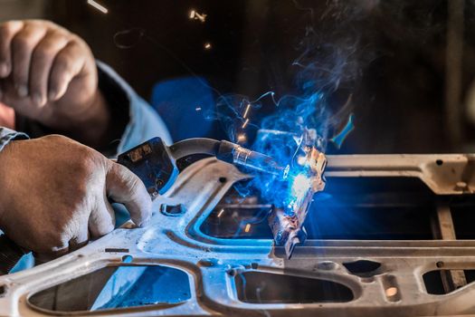 Close-up of welding works. Repair of automobile doors and metal works in industry.