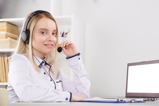 Portrait of happy smiling female customer support phone operator at workplace. - Image