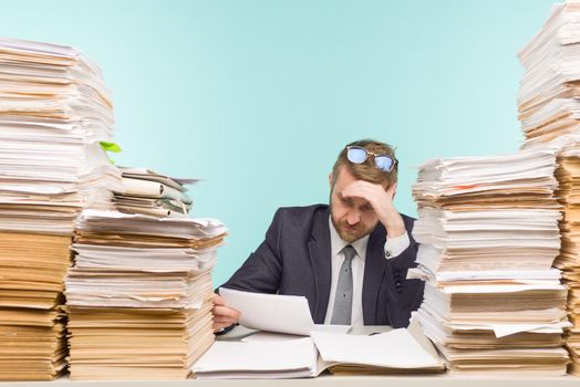 Business executive working in the office and piles of paperwork, he is overloaded with work - image