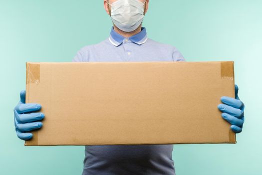 Man holding cardboard boxes in medical rubber gloves and mask. Coronavirus pandemic quarantine delivery concept