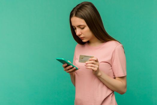 Photo of pleased happy screaming young woman posing isolated over blue wall background using mobile phone holding credit card. - image