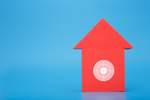 Mortgage, loan or saving money for home and investing in real estate trendy concept. Red toy house with white target in the middle against blue background with copy space