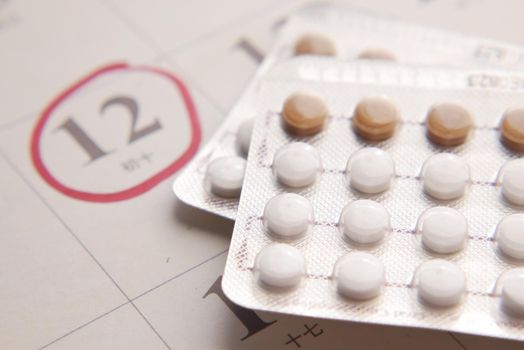 birth control pills , calendar on table close up .