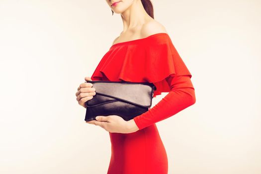 Beautiful fashion outfit, red dress and black big leather bag in hand of girl . Stylish accessory - Image