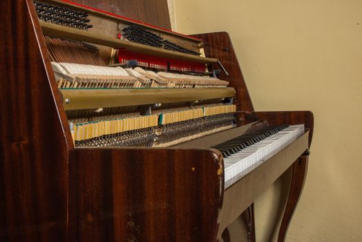 old broken piano standing at the wall