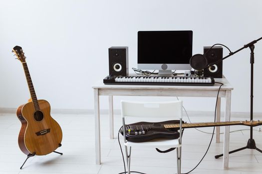 Microphone, computer and musical equipment guitars and piano background. Home recording studio.
