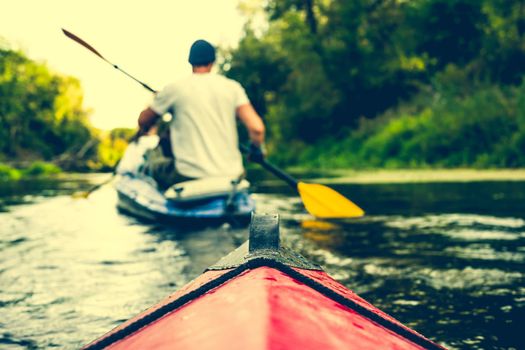 nose of canoe floating behind rower on a river