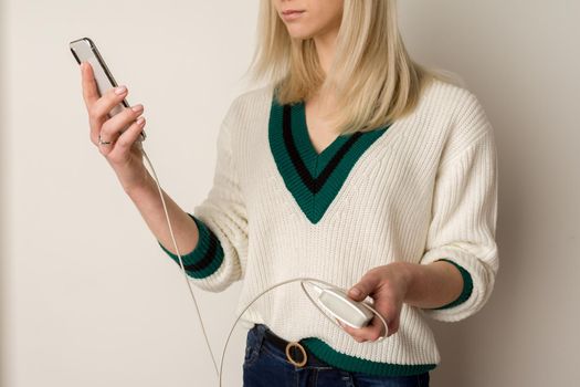 Thoughtful girl plays in the phone and infects it by power bank. Power bank in girl's hands. Using power bank and playing games.