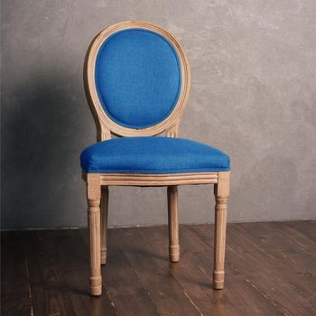 Blue luxurious vintage chair stands on a dark wooden floor.