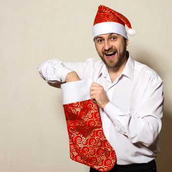 Surprised man in a Christmas cap pulls a gift out of sock