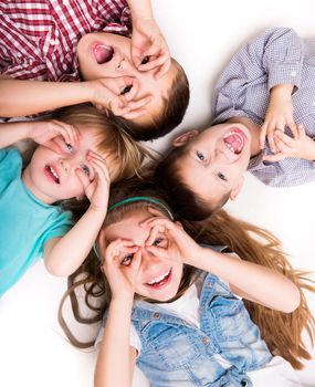 children lying on the floor with hands imitating glasses