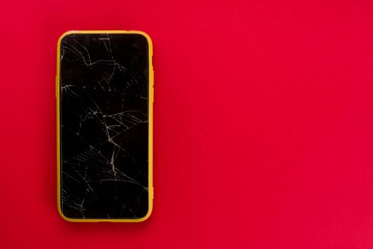Smartphone with broken screen on red background - image