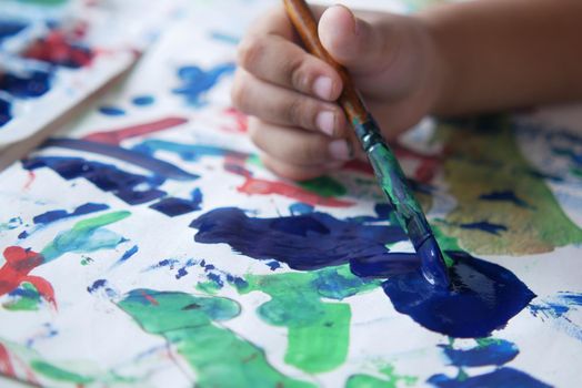 child hand drawing with art brush on a paper .