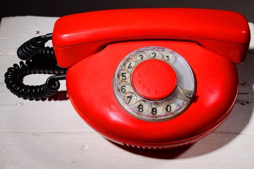 Red vintage phone on white wooden background
