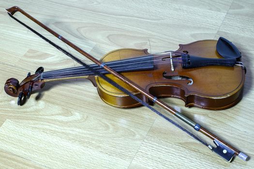 vintage violin with a bow lies on a wooden bench