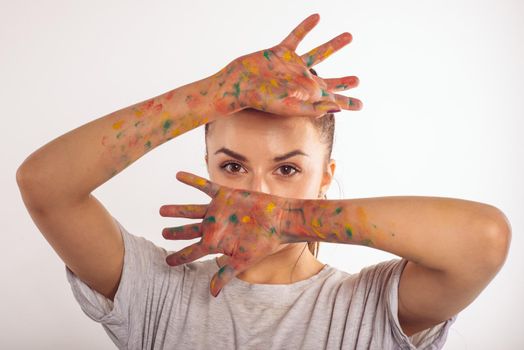 portrait teenage girl covers her face with her palms in paint isolated on white