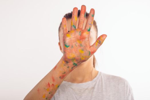 teenage girl covers her face with her left palm in paint