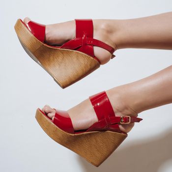 Beautiful female legs in red sandals on a wedge.