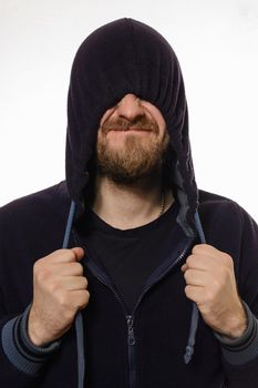 beard man pulled a hood over his eyes and smile while standing against white background