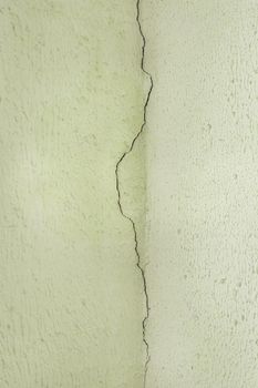 Crack on the old plaster wall surface in the ceiling corner of the building facade texture background.