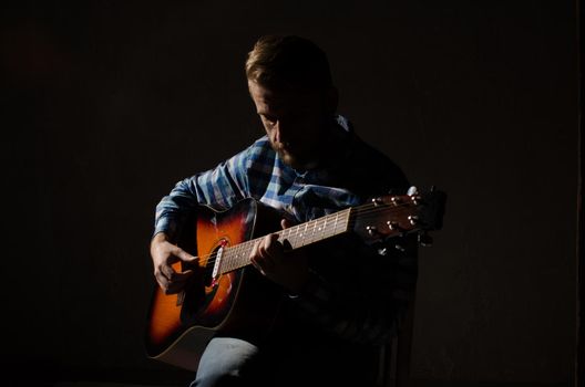 Portrait of Caucasian male musician playing guitar on stage, focus on hand.