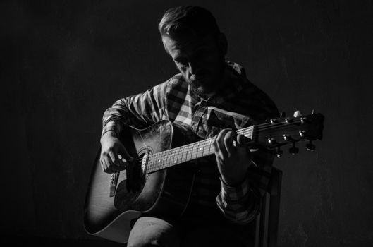 Caucasian male musician playing guitar on stage, focus on hand. black and white.