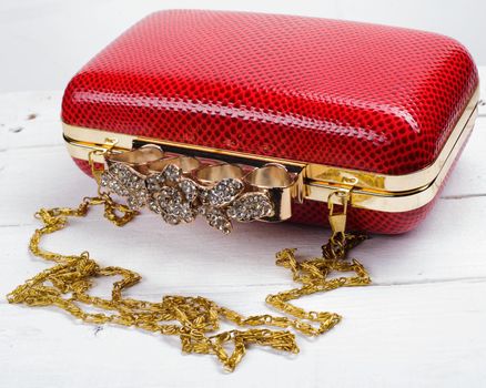 Red handbag clutch with chain on white background.