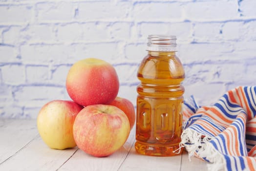 fresh apples and bottle of juice on table .